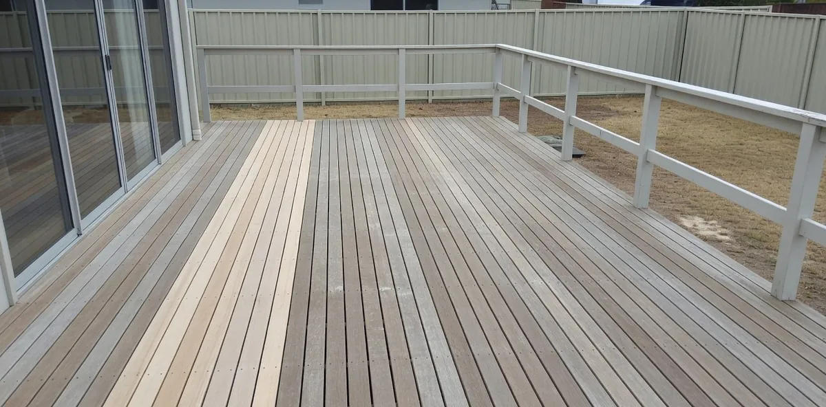 A whole back deck seen from one corner, part of it freshly sanded pale and part still weathered grey